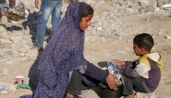A woman and a boy cover a pot filled with food they received after queueing with others for charity meals given out during the Muslim holy fasting month of Ramadan in Gaza City on March 22, 2025. Photo by BASHAR TALEB / AFP