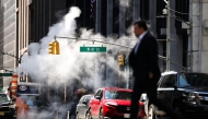 Steam rises from underground as pedestrians and cars move along the Sixth Avenue in the Manhattan borough of New York City on March 26, 2025. (Photo by CHARLY TRIBALLEAU / AFP)
