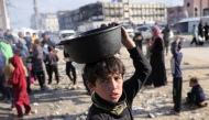 A boy walks with a pot of food he received after queueing for charity meals given out during the Muslim holy fasting month of Ramadan, in Gaza City on March 22, 2025. Photo by BASHAR TALEB / AFP