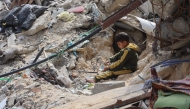 A Palestinian boy plays amidst the debris of a building destroyed during the Israel-Hamas war, in Gaza City on March 28, 2025. (Photo by Omar Al-Qattaa / AFP)
