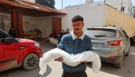 A man carries the body of a child, who was killed in an Israeli bombardment, at Al-Ahli Arab Hospital in Gaza City on March 26, 2025. Photo by Omar AL-QATTAA / AFP.
