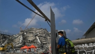 A man uses his smartphone to record at the site of an under-construction building collapse in Bangkok on March 29, 2025, a day after an earthquake struck central Myanmar and Thailand. (Photo by MANAN VATSYAYANA / AFP)