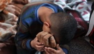 A boys mourns over the body of a loved one killed in overnight Israeli bombardment on northen Gaza, at the Ahli Arab Hospital, also known as the Maamadani (Baptist) Hospital, in Gaza City on April 3, 2025. (Photo by Omar AL-QATTAA / AFP)