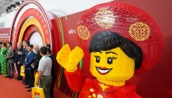Attendees take photos past a full-scale model made with Lego bricks during the inauguration of the Lego factory in Binh Duong Province on April 9, 2025. Photo by Huu Khoa / AFP