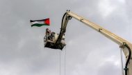 A demonstrator being raised by a crane holds up a Palestinian flag during a rally in solidarity with Palestinians in the Gaza Strip and in condemnation of US strikes, in Yemen's capital Sanaa on April 11, 2025. (Photo by Mohammed Huwais / AFP)
