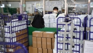 Stacked parcels are seen up front as a Hongkong Post employee stands at a service counter at a post office in Hong Kong on April 16, 2025. (Photo by Peter Parks / AFP)