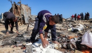 A boy salvages flour in the aftermath of a reported Israeli strike on a tent shelter in Khan Yunis in the southern Gaza Strip on April 17, 2025. Photo by Eyad BABA / AFP.