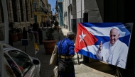 A man walks near a picture of the late Pope Francis on a street in Havana on April 22, 2025. (Photo by Yamil Lage / AFP)
