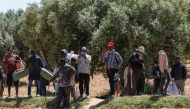 People leave with their belongings from a makeshift camp for migrants from sub-Saharan Africa as authorities dismantle the camp at al-Amra on the outskirts of the Tunisian city of Sfax on April 24, 2025. (Photo by Mohamed KHALIL / AFP)
