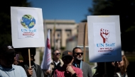Geneva based United Nations employees hold slogans during a demonstration in Geneva, on May 1, 2025, over deep funding cuts, especially from key donor the United States, which have led to mass-layoffs and threatened life-saving services around the world. (Photo by Fabrice COFFRINI / AFP)