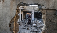 A man carries salvaged concrete blocks inside a building hit in an Israeli strike in the Bureij camp for Palestinian refugees in the central Gaza Strip on May 2, 2025. (Photo by Eyad BABA / AFP)