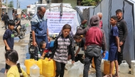 A Palestinian girl ferries water containers back from a distribution point at the Nuseirat refugee camp in the central Gaza Strip on May 5, 2025. (Photo by Eyad BABA / AFP)