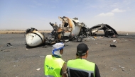 Airport employees stand next to a destroyed plane at the Sanaa International Airport on May 7, 2025. (Photo by Mohammed Huwais / AFP)
