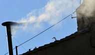 This photograph shows white smoke rising from the chinmey of the Sistine Chapel signaling that cardinals elected a new pope during their conclave in the Vatican on May 8, 2025. (Photo by Alberto PIZZOLI / AFP)