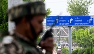 An Indian paramilitary personnel uses a handheld transceiver as he stands guard along a street leading to the international airport in Srinagar on May 10, 2025. (Photo by Sajjad Hussain / AFP)