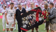Bayern Munich's German forward #25 Thomas Mueller (L) is handed by Bayern Munich's President Herbert Hainer a picture showing Muller inmid trophies ahead the German first division Bundesliga football match between Bayern Munich and Borussia Moenchengladbach in Munich on May 10, 2025. (Photo by Alexandra BEIER / AFP)