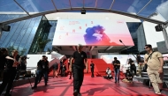 An employee (C) unrolls the red carpet at the Palais des Festivals ahead of the opening ceremony 78th Cannes Film Festival in Cannes, south-eastern France, on May 13, 2025. (Photo by Bertrand Guay / AFP)