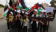 Palestinian children hold up a cutout symbolising the key to houses left by Palestinians in 1948 as they take part in a rally to commemorate the 77th anniversary of the 