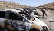 A Palestinian man looks at burnt out vehicles in the Barkan Industrial area, near Salfit in the occupied West Bank on May 16, 2025. (Photo by Jaafar Ashtiyeh / AFP)