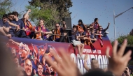 Barcelona's German coach Hans-Dieter Flick (C) and players ride in an open top bus to celebrate winning their 28th La Liga title in Barcelona, on May 16, 2025. (Photo by Manaure Quintero / AFP)