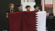 Young Qatar gymnasts celebrate with the national flag after securing bronze at the West Asian Championship.