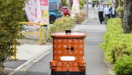 This photo taken on May 15, 2025 shows an automated robot on wheels from convenience store chain 7-Eleven delivering items during a demonstration in the Hachioji area of Tokyo. (Photo by JIJI Press / AFP) 