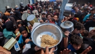 Palestinians gather to receive a hot meal at a food distribution point in the Nuseirat camp for refugees in the central Gaza Strip on May 21, 2025. (Photo by Eyad Baba / AFP)