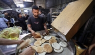 Employees of a bakery in Deir el-Balah in the central Gaza Strip, fill bags with freshly-baked bread, after Israel allowed limited humanitarian aid to enter the Palestinian territory on May 22, 2025. (Photo by Eyad Baba / AFP)
