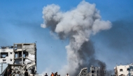 People move past destroyed buildings as smoke billows following an Israeli strike in Jabalia, in the northern Gaza Strip on May 25, 2025. (Photo by Bashar Taleb / AFP)

