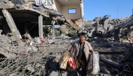 A Palestinian man carries items he salvaged from a house targeted in an Israeli strike at the Nuseirat camp for refugees in the central Gaza Strip on May 24, 2025. (Photo by Eyad BABA / AFP)
