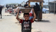 A Palestinian boy is seen with free food received from a food distribution center in Gaza City, on May 22, 2025. (Photo by Rizek Abdeljawad/Xinhua)
