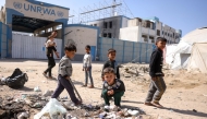 Children play around waste in front of the closed UN agency for Palestinian refugees UNRWA headquarters in Gaza City, on May 20, 2025. Photo by Bashar TALEB / AFP.
