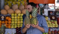 A man holds two pineapples at a stall that sells fruits in the Shalaan Market in the Syrian capital Damascus on May 26, 2025. (Photo by Louai Beshara / AFP)