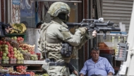 Photo used for representational purposes. An Israeli occupation soldier aims his rifle as a Palestinian man looks on during a raid in the heart of the Palestinian city of Nablus, in the occupied West Bank on May 27, 2025. Photo by Jaafar ASHTIYEH / AFP.