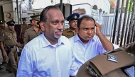 Sri Lanka's former sports minister Mahindananda Aluthgamage (left) and former trade minister Anil Fernando are escorted by police outside a court in Colombo on May 29, 2029 (Photo by Ishara S. Kodikara/ AFP)