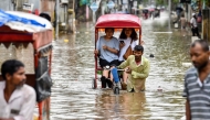 Women commute in cycle rickshaws through a flooded street after heavy rains in Guwahati, in India's Assam state on May 31, 2025. (Photo by Biju Boro / AFP)