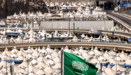 A Saudi flag flies as behind are pictured tents housing Muslim pilgrims in Mina near Islam's holy city of Mecca ahead of the annual Hajj pilgrimage on June 1, 2025. (Photo by Hazem Bader / AFP)

