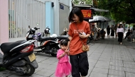 A mother takes her child to kindergarten in Hanoi on June 4, 2025. (Photo by Nhac Nguyen / AFP)