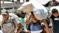 Photo used for representational purposes. Displaced Palestinians receive humanitarian aid packages from a US-backed foundation in Rafah in the southern Gaza Strip on June 10, 2025. Photo by AFP.
