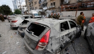 Rescuers work near a damaged building and damaged cars following a strike by an Iranian missile in the Israeli city of Bnei Brak, east of Tel Aviv, on June 16, 2025. (Photo by Jalaa Marey / AFP)