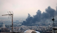 Smoke billows from an explosion near the Azadi Tower (L) in Tehran on June 16, 2025. (Photo by Atta Kenare / AFP)