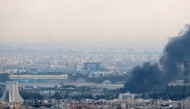 Smoke billows from a site near the Azadi Tower (L) in central Tehran, as fighting between Israel and Iran continues on June 16, 2025. Photo by ATTA KENARE / AFP.
