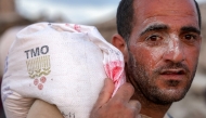 A man walks with a sack of flour on his back with others along al-Rashid street in western Jabalia on June 17, 2025, after humanitarian aid trucks reportedly entered the northern Gaza Strip through the Israeli-controlled Zikim border crossing. Photo by BASHAR TALEB / AFP.
