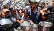 Palestinians try to get food at a charity kitchen providing hot meals in Rimal neighbourhood in Gaza City on June 18, 2025. Photo by Omar AL-QATTAA / AFP