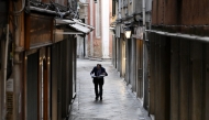 Photo used for representational purposes. A man reads a newspaper as he walks in a narrow street of venice, on June 24, 2025. Photo by Stefano RELLANDINI / AFP.