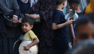 Palestinians line up to receive a hot meal at a food distribution point in Gaza City on June 27, 2025. Photo by BASHAR TALEB / AFP