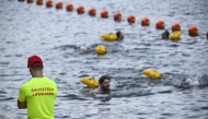 A lifeguard stands on duty as people swim at the Pont Marie safe bathing site on the Seine river on its opening day, in Paris on July 5, 2025. Photo by JULIEN DE ROSA / AFP.
