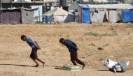 Palestinian boys drag bags of items salvaged from a garbage waste dump in the Al-Bureij camp in the central Gaza Strip on July 7, 2025. (Photo by Eyad BABA / AFP)