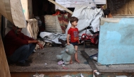 A Palestinian child holds a stuffed animal while standing at a school sheltering displaced Palestinians which was hit by an Israeli strike in the Al-Bureij camp in the central Gaza Strip on July 8, 2025. Photo by Eyad BABA / AFP