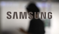 A woman walks past a logo of Samsung Electronics displayed on a glass door at the company's Seocho building in Seoul on July 8, 2025. Photo by Jung Yeon-je / AFP